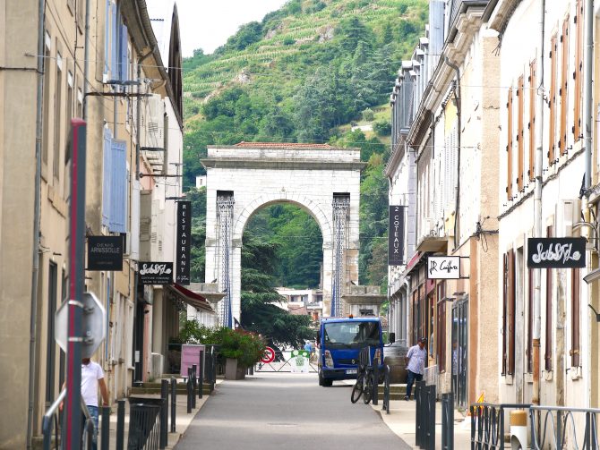 Provenzalische Gasse in Tain-l’Hermitage mit Blick auf eine historische Brücke – charmante Impression entlang der Flusskreuzfahrt.
