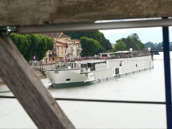 Blick durch das Brückengeländer auf den Flusskreuzer Ravel von Riverside Cruises – stilvolle Provence-Reise auf der Rhône.